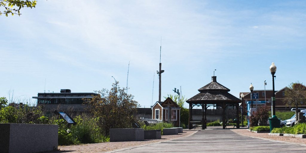 a boardwalk in a park with a gazebo and buildings