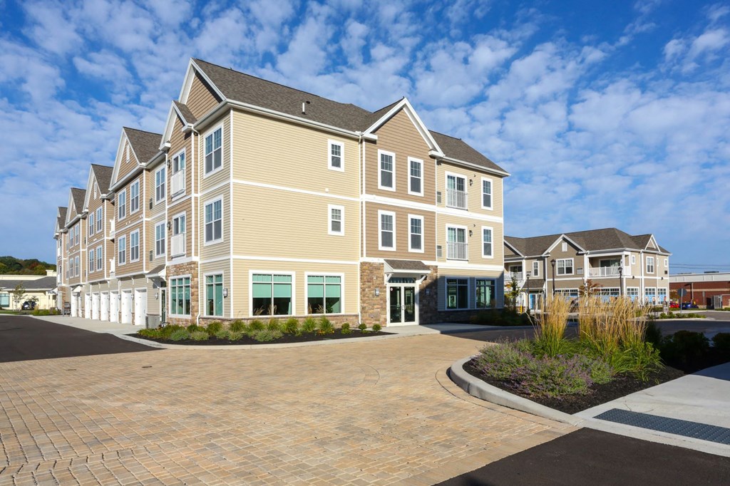 a row of town homes with a brick driveway and a blue sky