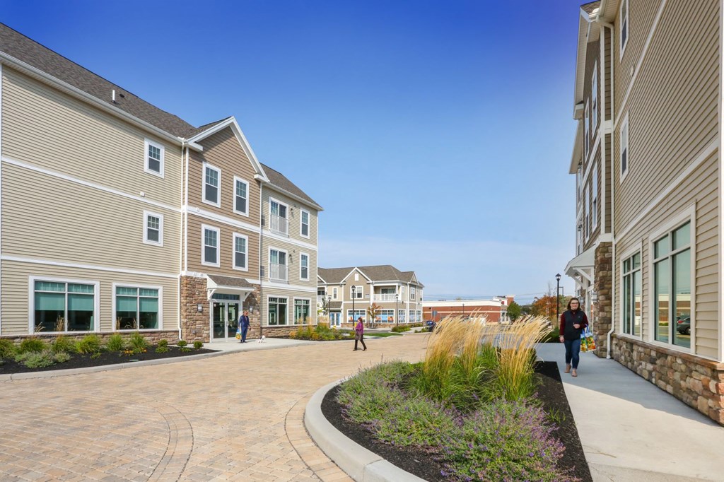 people walking down a street in front of apartments