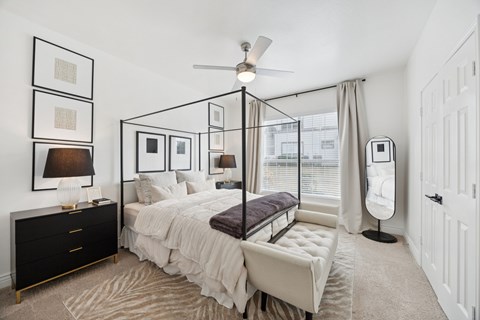 A bedroom with a four poster bed and a ceiling fan.