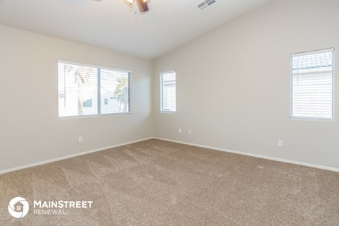 a spacious living room with carpet and two windows