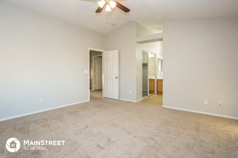 a spacious living room with carpet and a ceiling fan