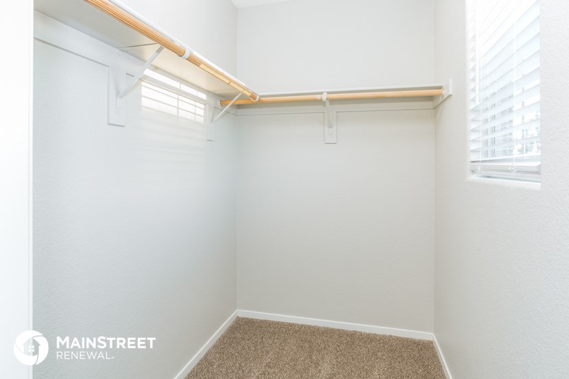 an empty closet with a window and white walls