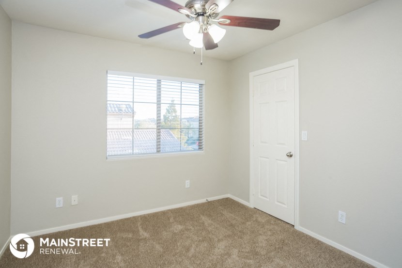 the spacious living room with ceiling fan and window