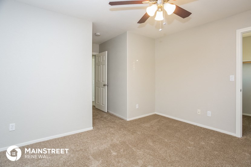the spacious living room with ceiling fan and carpeted flooring