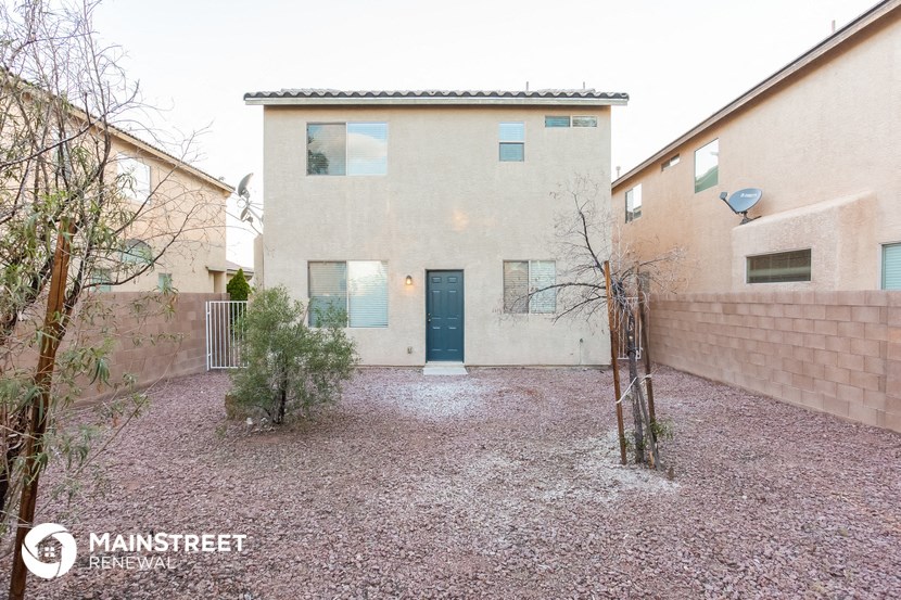 a white house with a blue door and a gravel yard