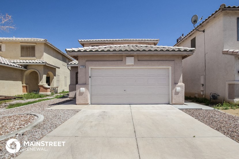 a white garage door on a beige house with a driveway