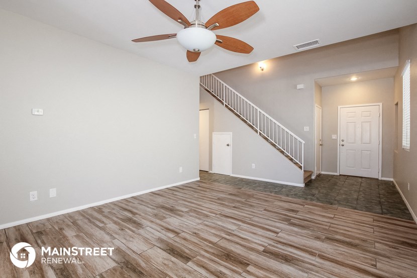the spacious living room with wood flooring and a ceiling fan