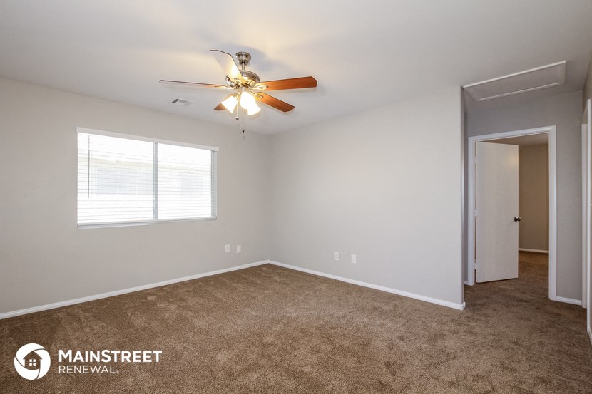 the spacious living room with carpeting and a ceiling fan