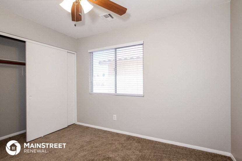 a bedroom with a ceiling fan and a closet