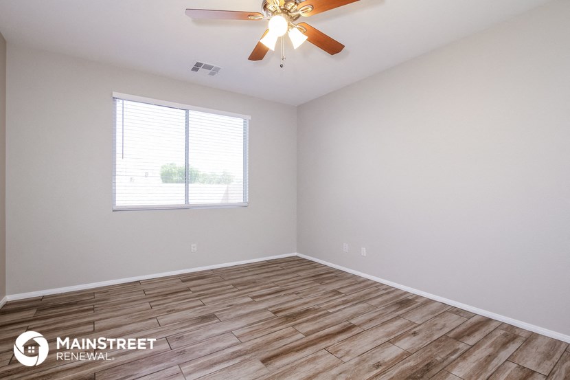 the spacious living room with wood flooring and a ceiling fan