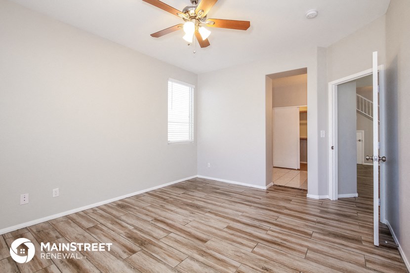 the spacious living room with wood flooring and a ceiling fan
