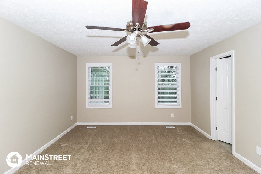 the master bedroom has a ceiling fan and a carpeted floor