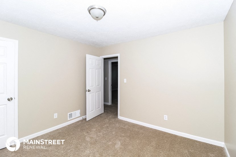 the spacious living room with carpeting and a door to the hallway
