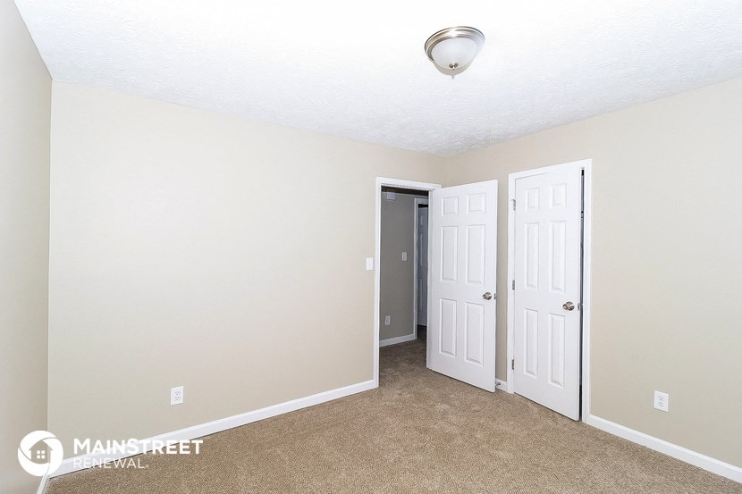 a bedroom with two doors and a carpeted floor
