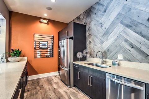 A kitchen with a stainless steel refrigerator and a wooden floor.