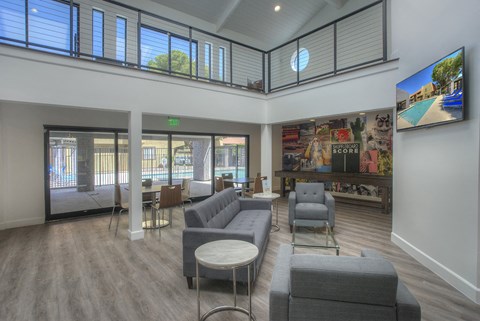 A living room with grey couches and a television on the wall.