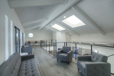 A spacious room with grey furniture and a skylight.