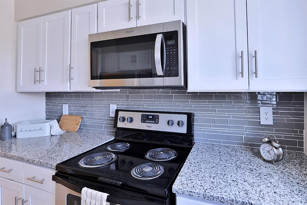 a kitchen with white cabinets and a stove and a microwave