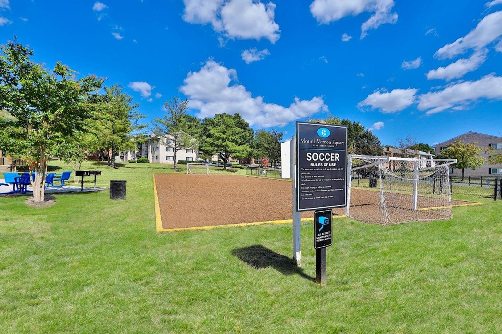 a park with a volleyball court and a sign in the grass