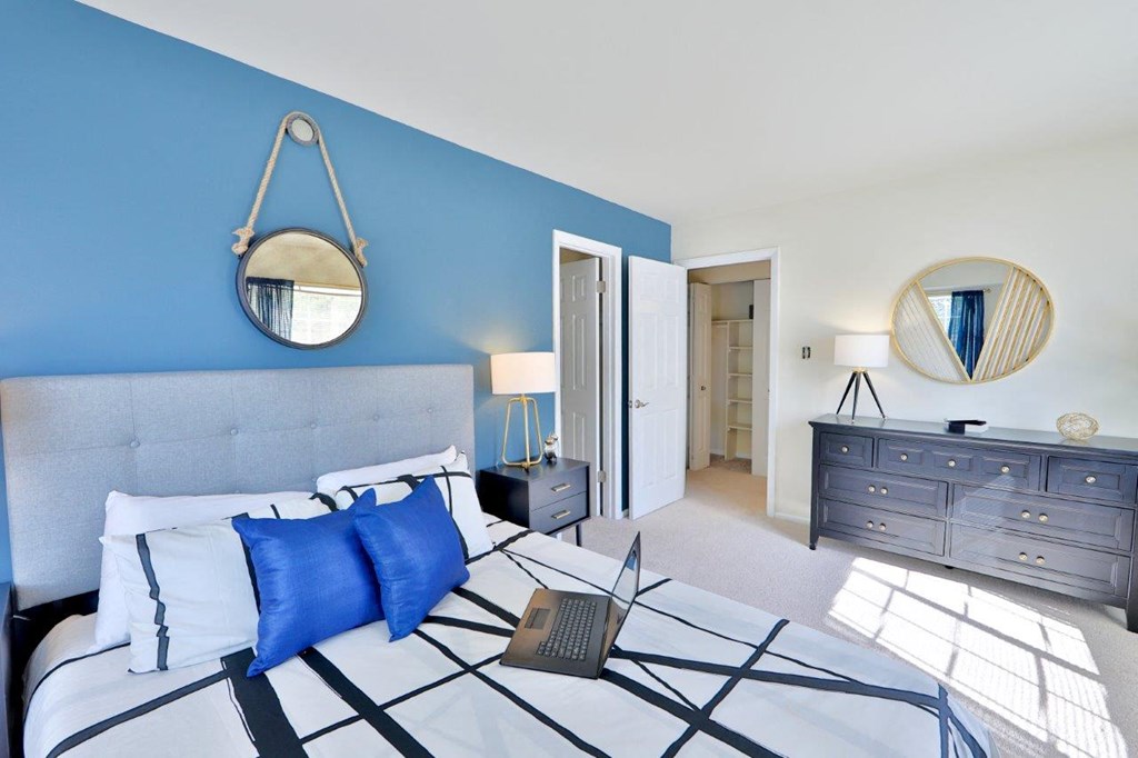 a bedroom with blue walls and a bed with a laptop on it