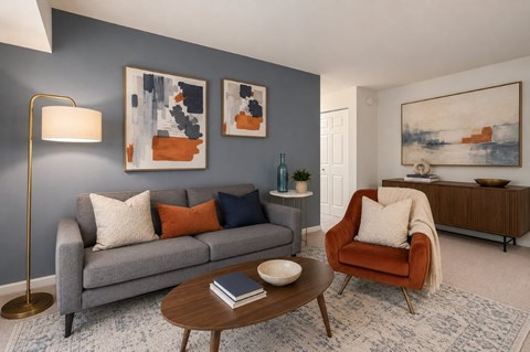 A living room with a grey couch, a red chair, and a coffee table.