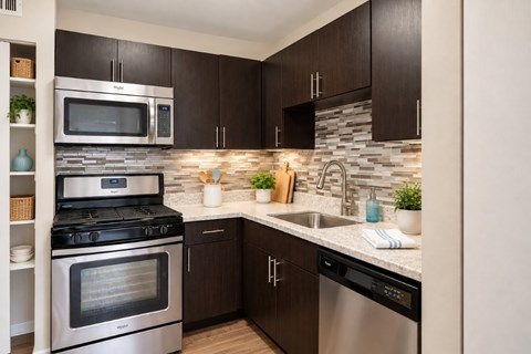 A modern kitchen with dark brown cabinets and stainless steel appliances.