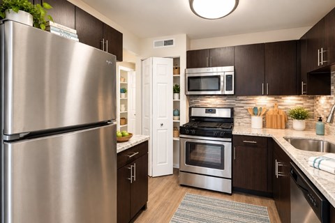 A modern kitchen with dark brown cabinets and stainless steel appliances.