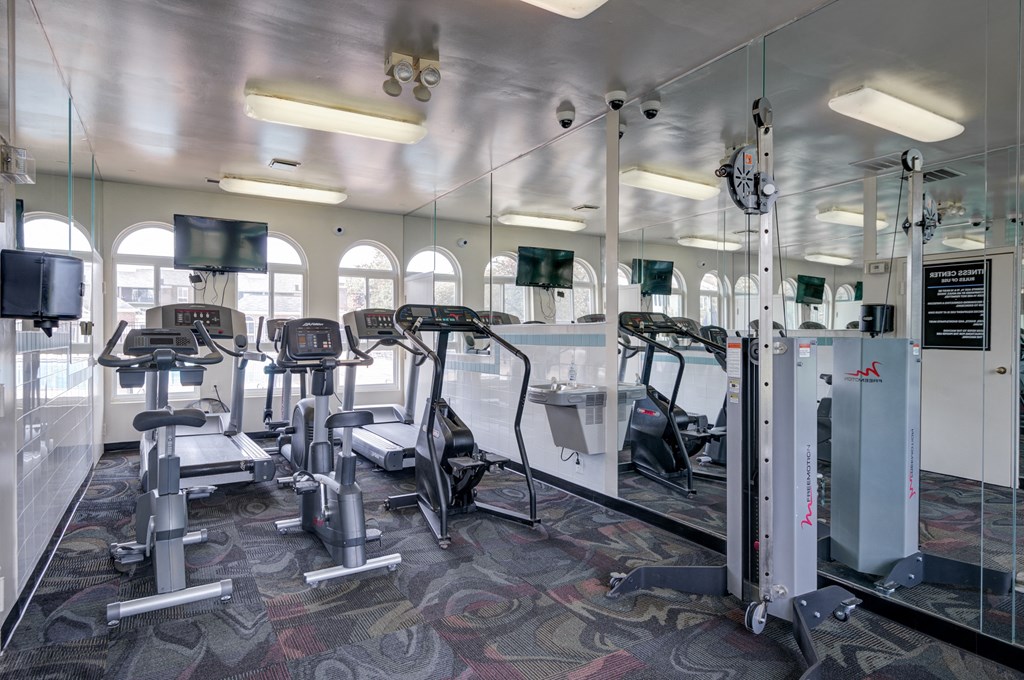 a gym with cardio equipment and windows