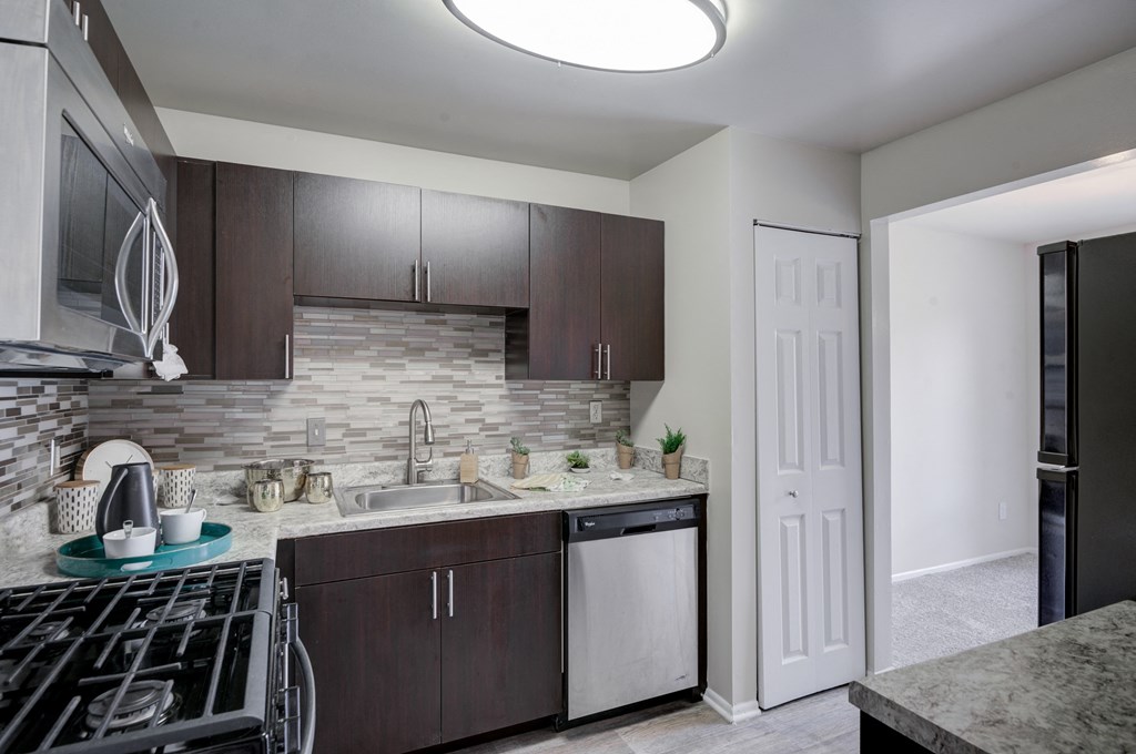 a kitchen with dark cabinets and a stove and a sink
