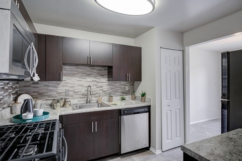 a kitchen with dark cabinets and a stove and a sink