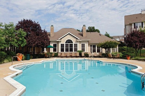 a large swimming pool with a house in the background