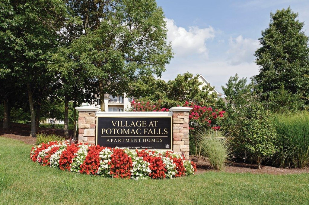 the sign for thevillage at potomac falls sign with flowers around it