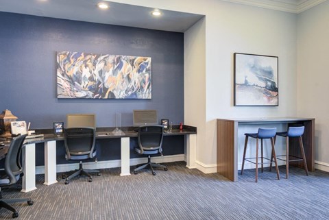 a conference room with desks and chairs and a painting on the wall