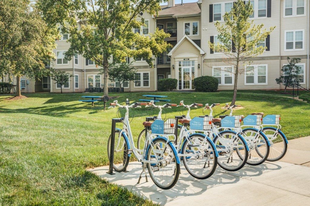 a row of blue bikes parked in front of an apartment building