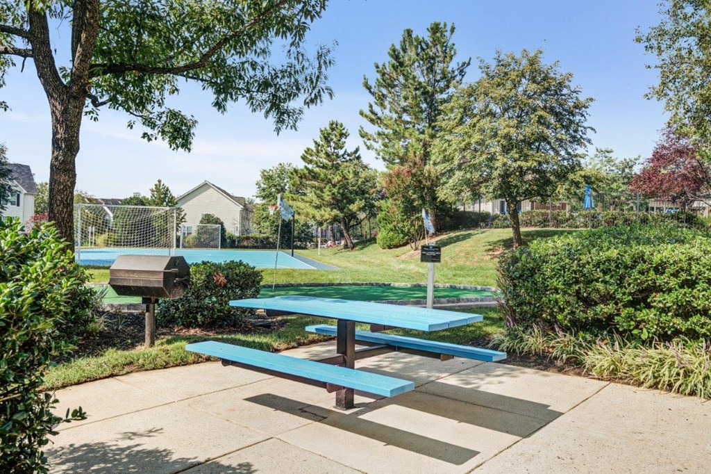 a picnic table in a park with a basketball court