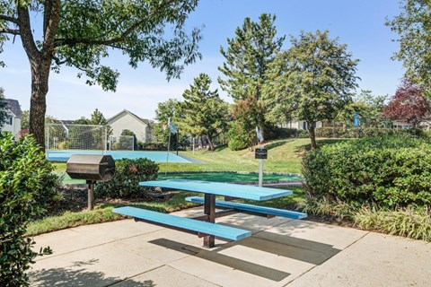 a picnic table in a park with a basketball court