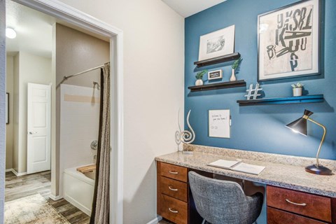 a home office with a desk and a bathroom with a shower