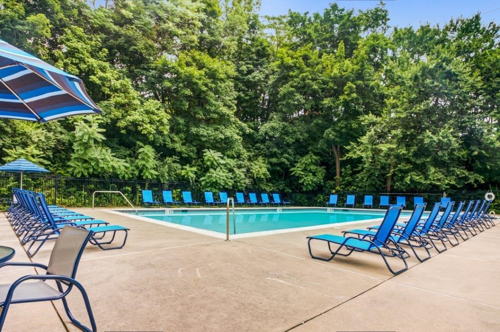 a swimming pool with blue lounge chairs and umbrellas