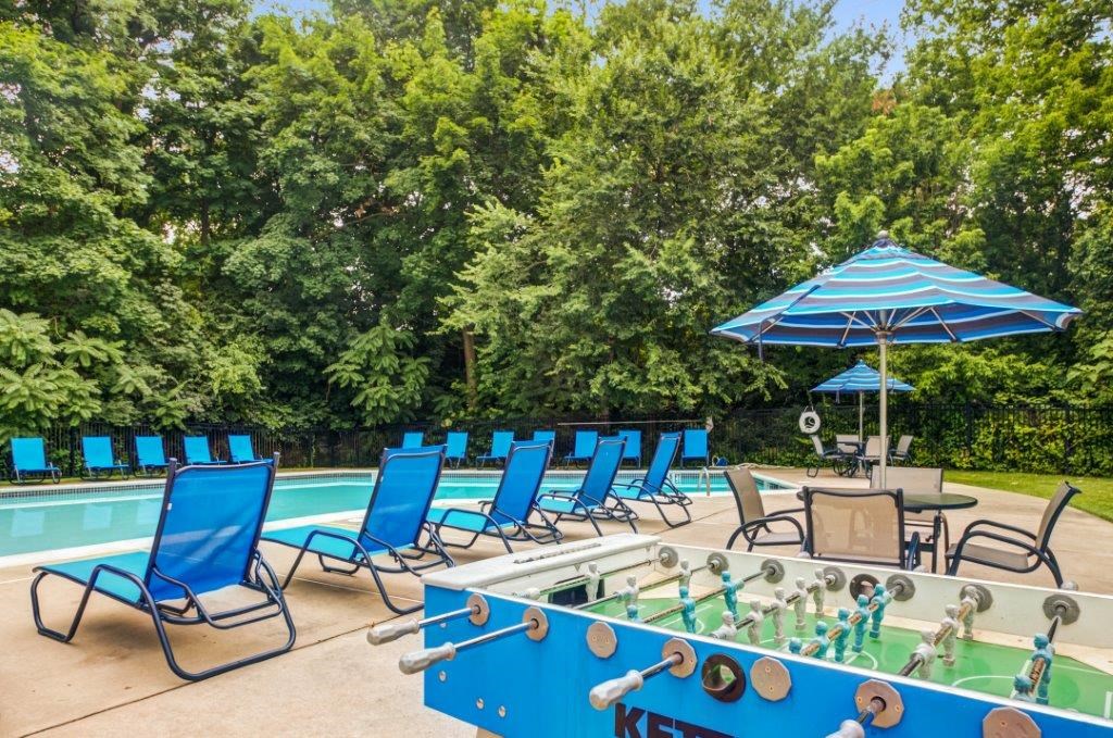 a swimming pool with blue lounge chairs and a poolside chess game