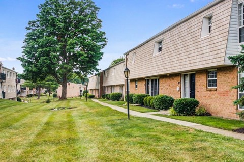 a row of brick apartment buildings with grass and a sidewalk