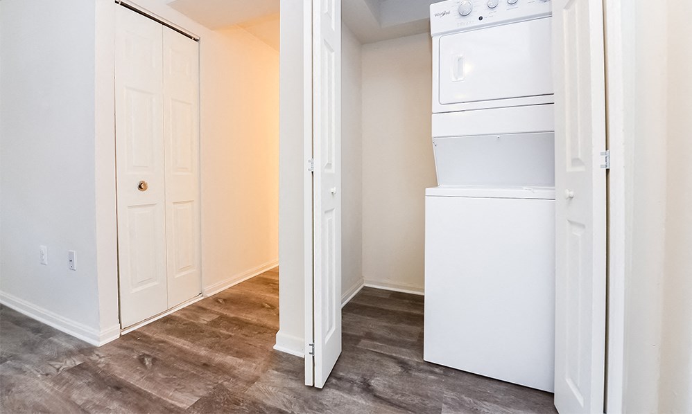 an empty room with a washer and dryer and a door to a closet