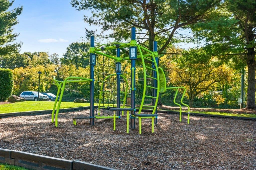 a playground in a park with a blue and green swing set