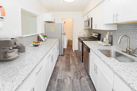 a large kitchen with white cabinets and marble counter tops