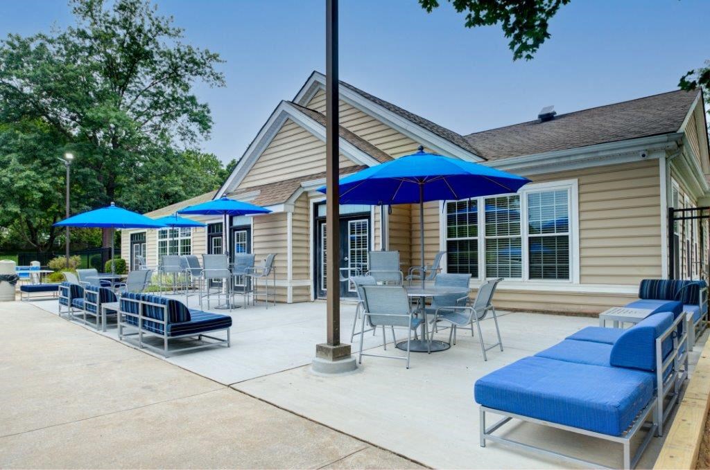 a patio with tables chairs and umbrellas outside of a house