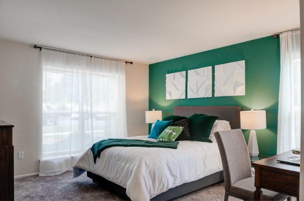 a bedroom with a green accent wall and a white bed