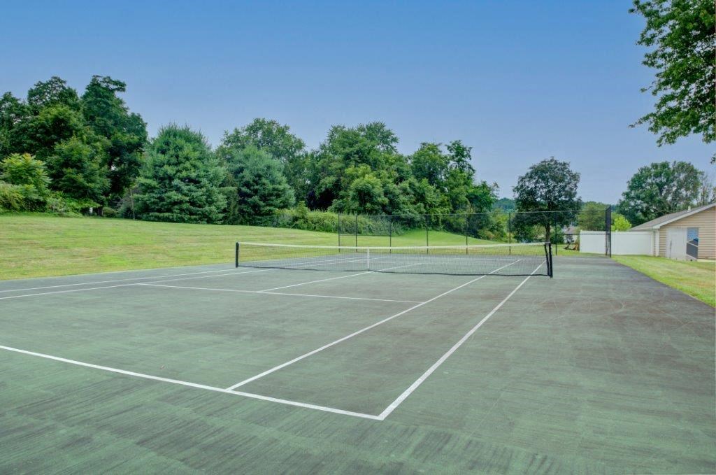 a tennis court with trees in the background on a sunny day