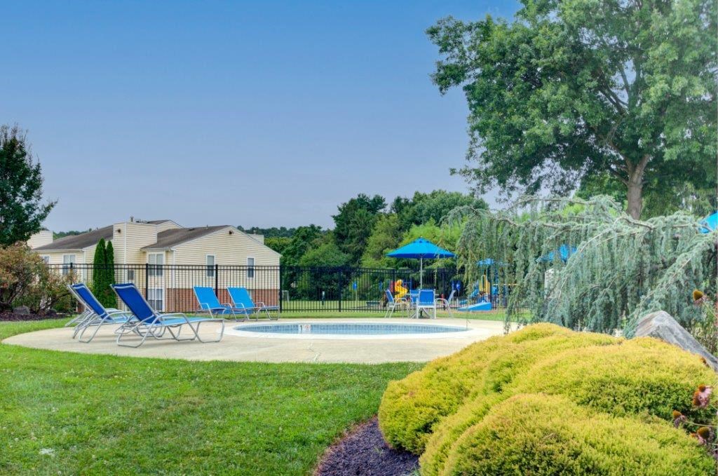 a yard with a pool and chairs and a house