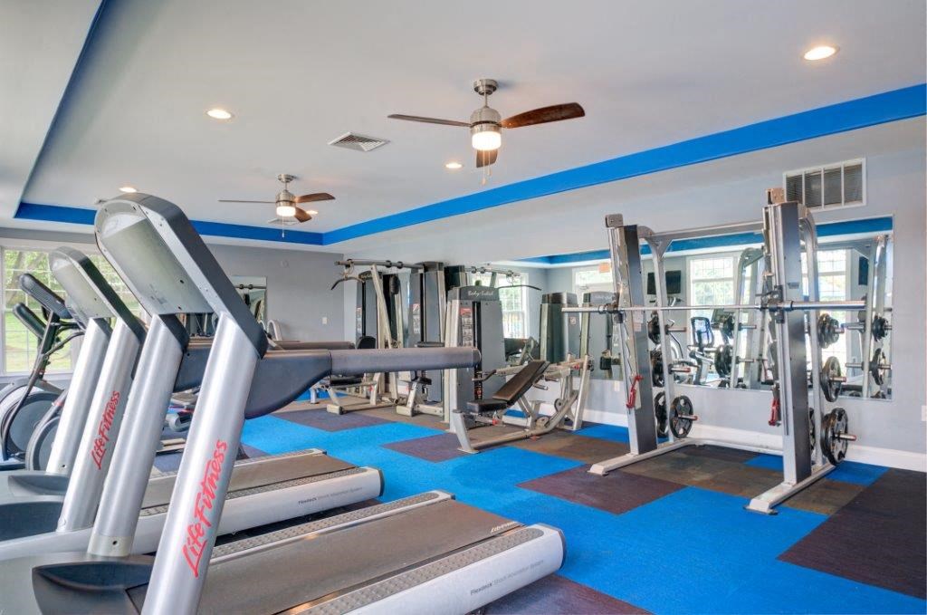 a gym with cardio equipment and a ceiling fan