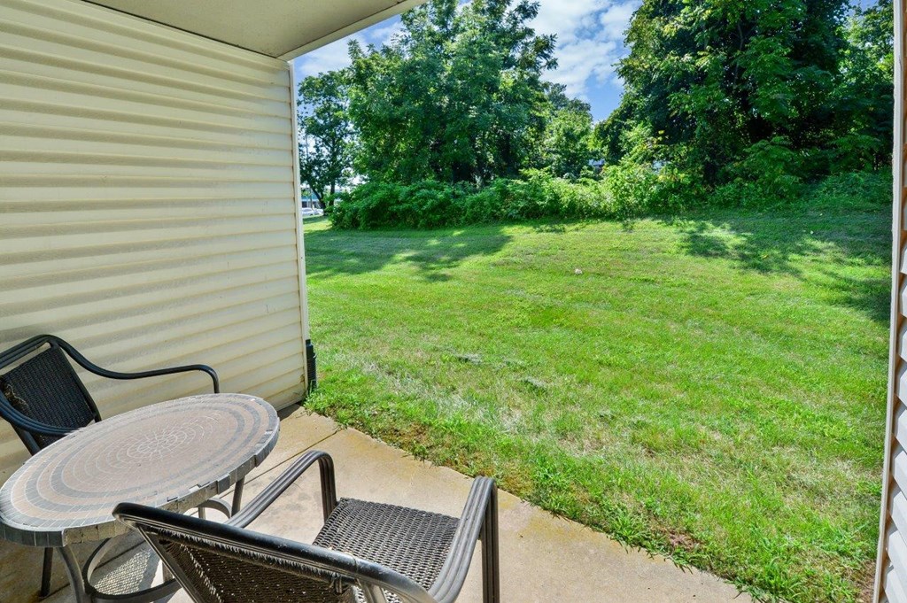 a patio with a table and chairs and a grassy yard
